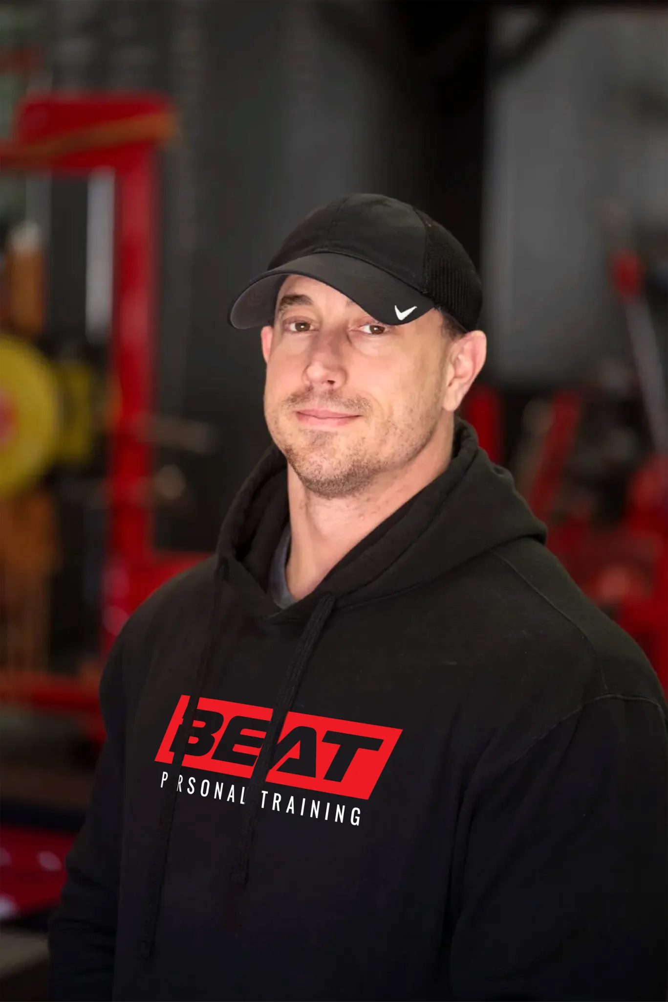 Man in a black cap and BEAT hoodie at the gym.
