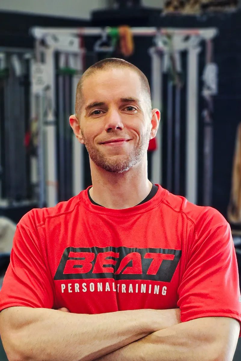 Personal trainer in a gym wearing a red Beat Personal Training shirt.